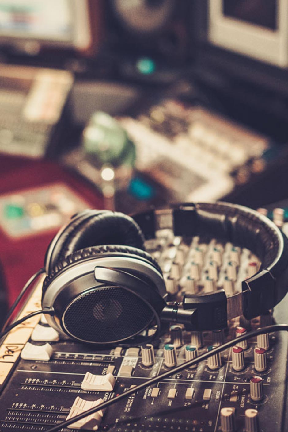 Headphones resting on a mixing console in a recording studio, representing music and audio production training.