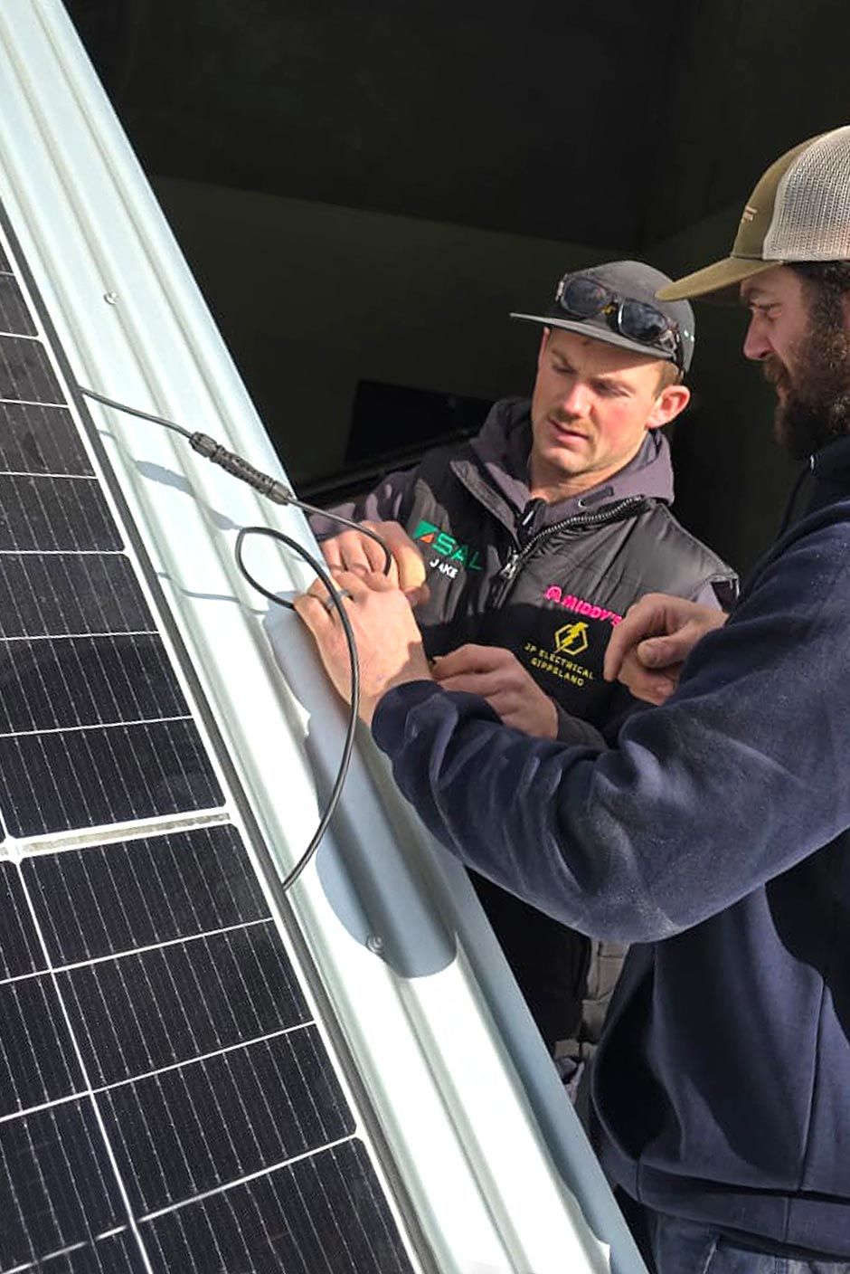 Two electricians practising connect and disconnect procedures on a solar panel during hands-on training.