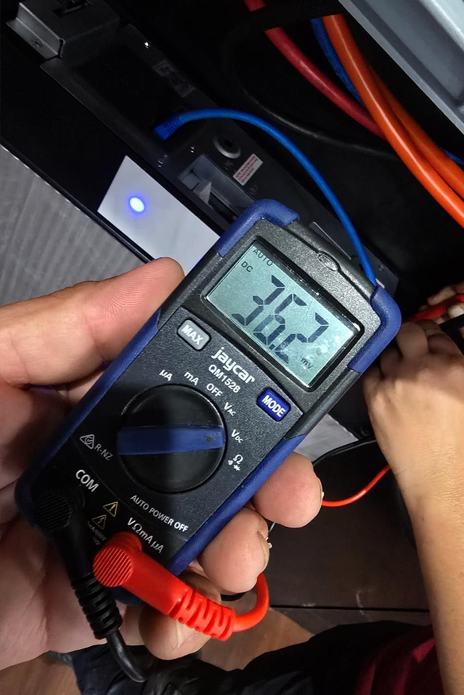 Close-up of a technician using a digital multimeter to test voltage during Level 2 ASP electrical training.