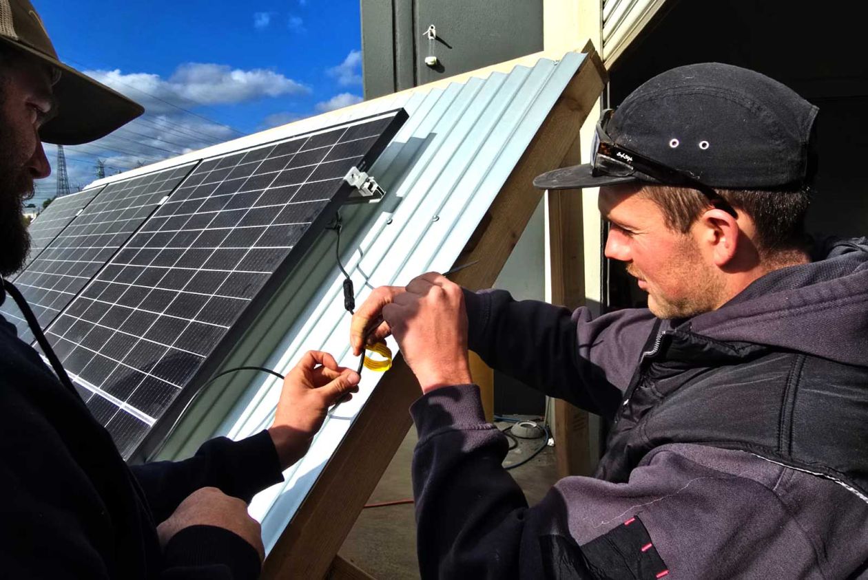 Students practising solar wiring connections on an outdoor training rig during a hands-on class
